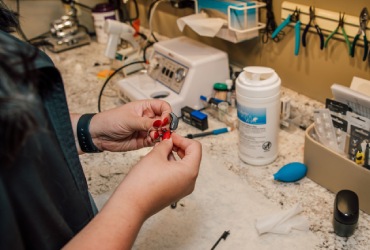 A audiologist repairs hearing aid